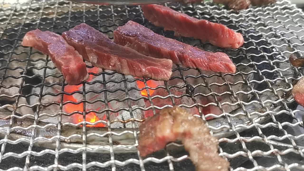 在豪华的韩式牛排烧烤(BBQ)餐厅里，新鲜的和牛牛肉在炭火上烧烤。视频素材