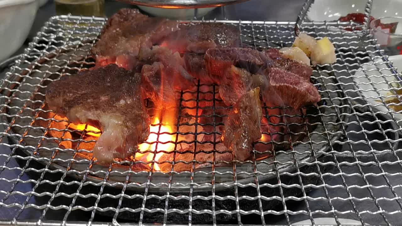 在豪华的韩式牛排烧烤(BBQ)餐厅里，新鲜的和牛牛肉在炭火上烧烤。视频下载