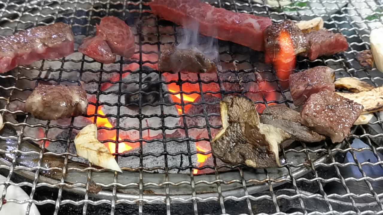 在豪华的韩式牛排烧烤(BBQ)餐厅里，新鲜的和牛牛肉在炭火上烧烤。视频素材