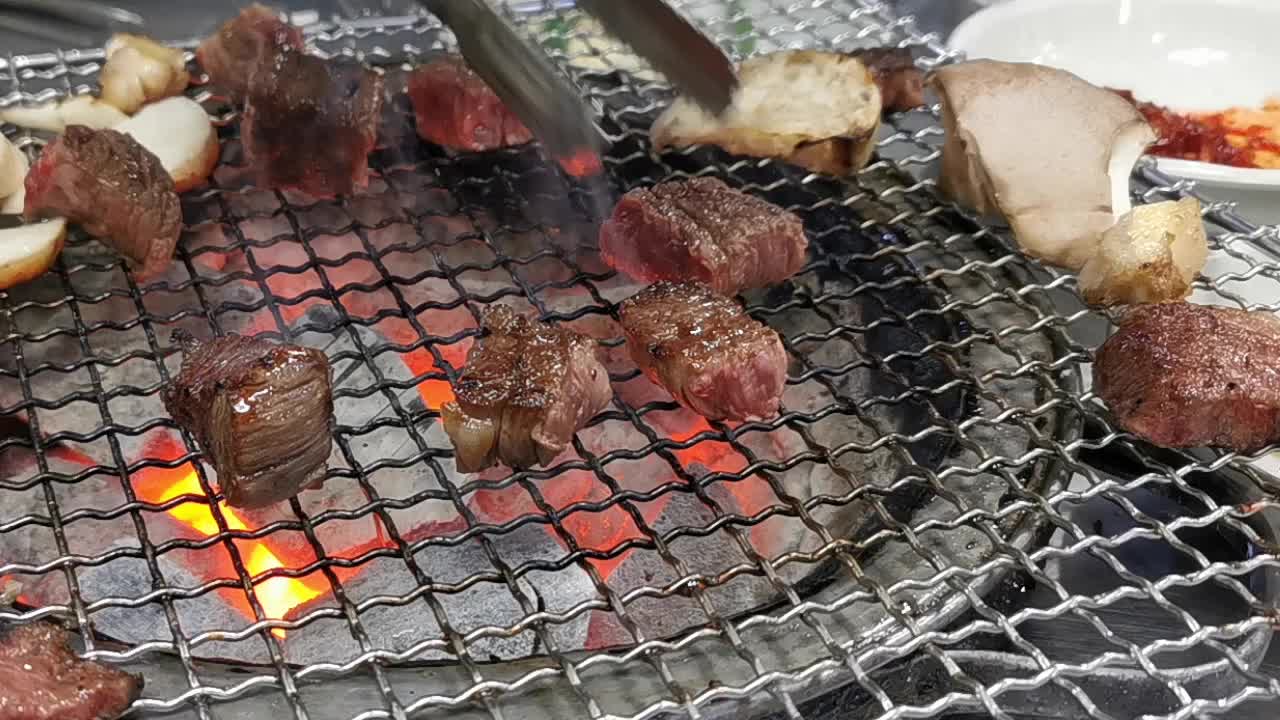 在豪华的韩式牛排烧烤(BBQ)餐厅里，新鲜的和牛牛肉在炭火上烧烤。视频下载