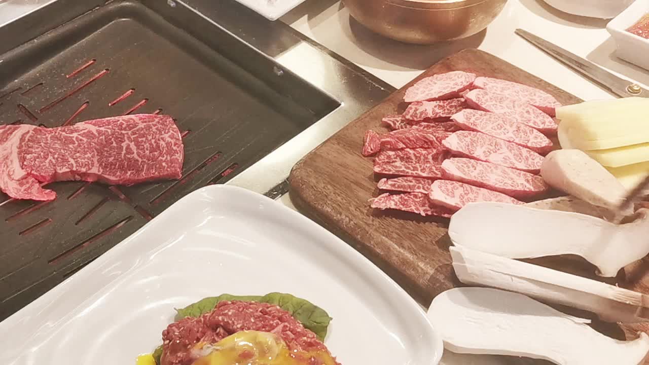 在豪华的韩式牛排烧烤(BBQ)餐厅里，新鲜的和牛牛肉在炭火上烧烤。视频下载