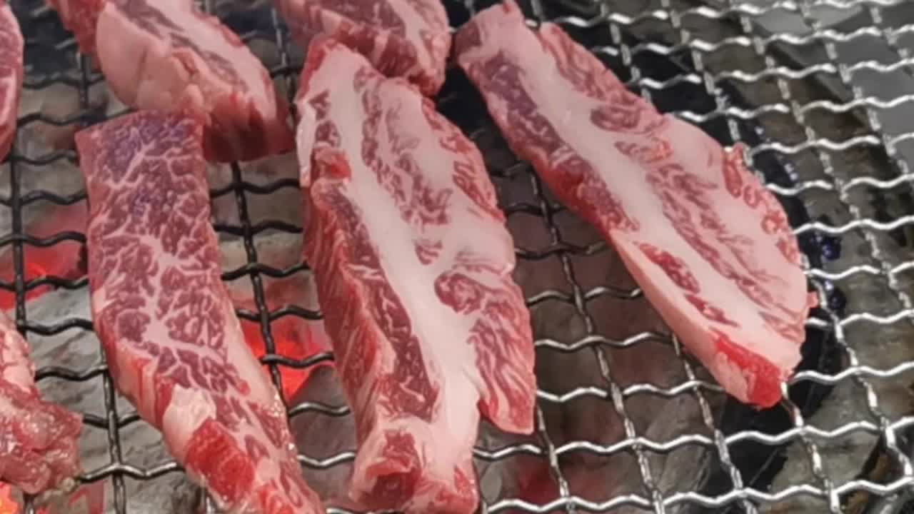 在豪华的韩式牛排烧烤(BBQ)餐厅里，新鲜的和牛牛肉在炭火上烧烤。视频素材