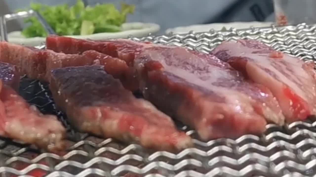 在豪华的韩式牛排烧烤(BBQ)餐厅里，新鲜的和牛牛肉在炭火上烧烤。视频素材