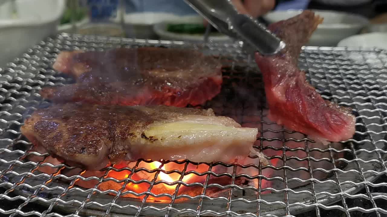 在豪华的韩式牛排烧烤(BBQ)餐厅里，新鲜的和牛牛肉在炭火上烧烤。视频下载