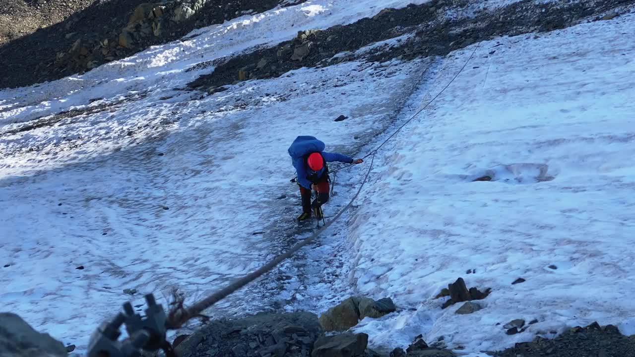 登山者靠在登山杆上，沿着冰碛行走，用一根绳子沿着一根绳子移动视频素材