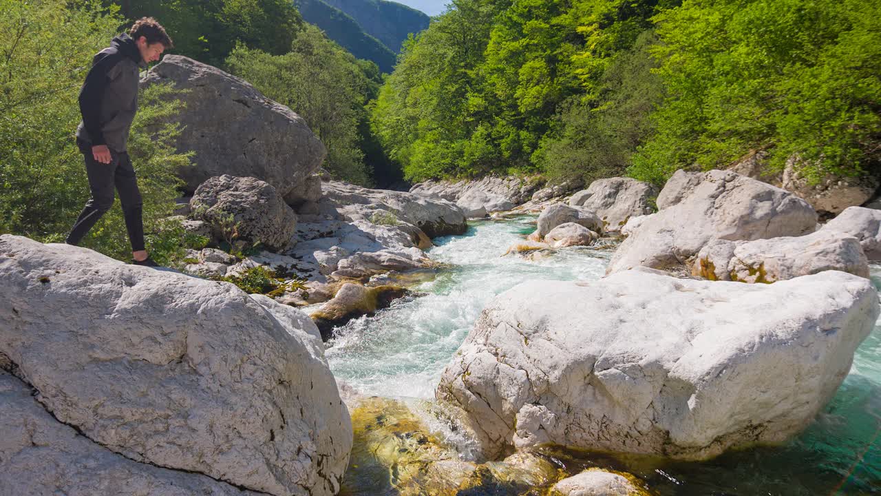 徒步旅行者穿越河流在山，跳过水与惊人的背景风景视频素材