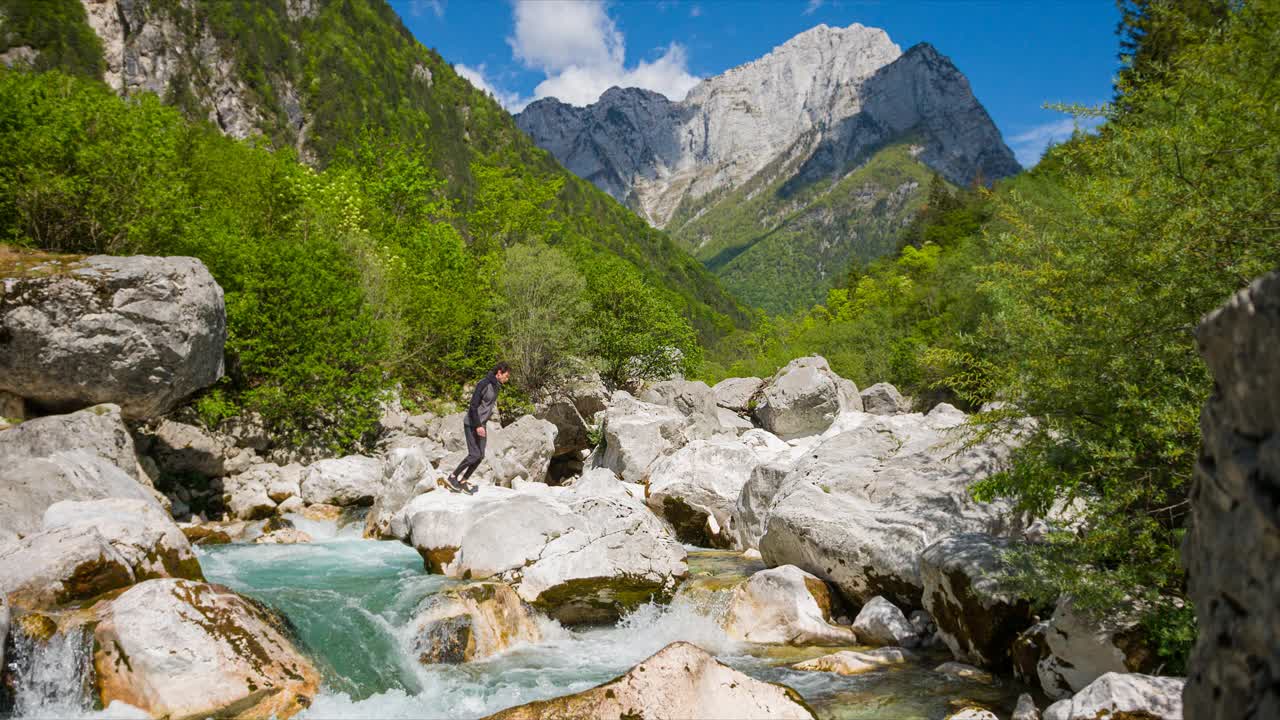 徒步旅行者跨越河流在山跳过水视频素材