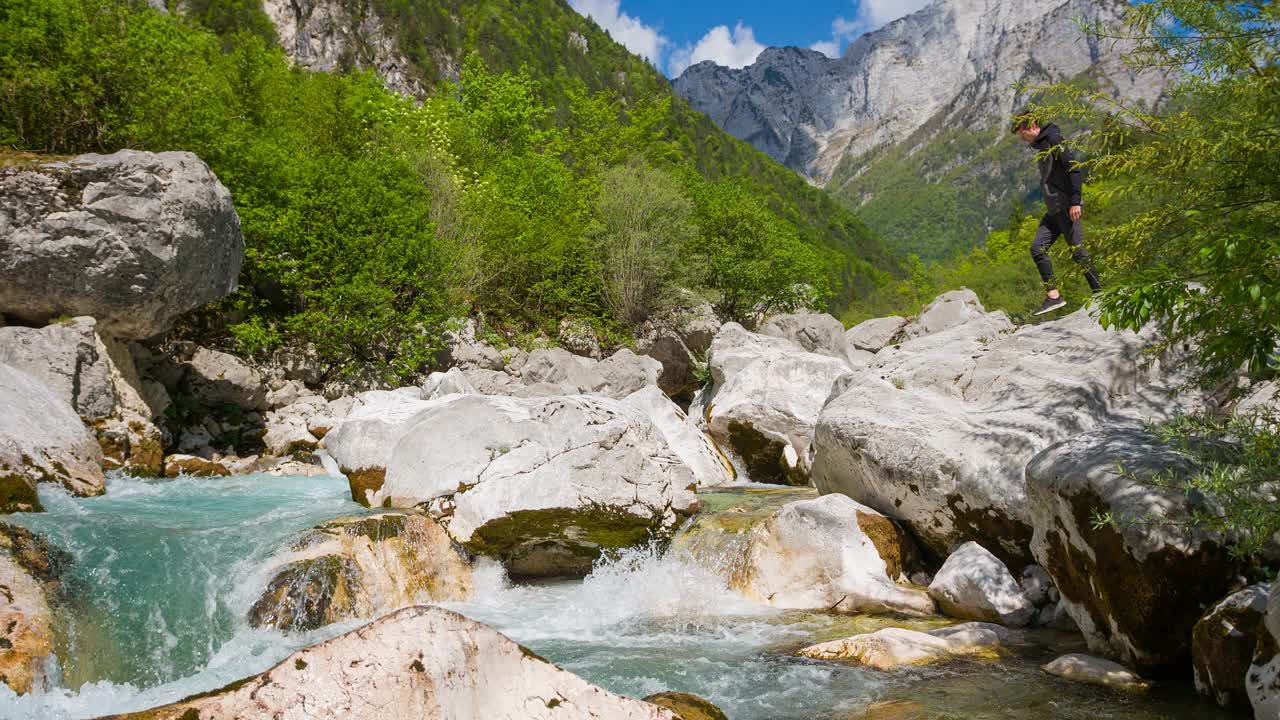 徒步旅行者跨越河流在山跳水雄伟葱郁的环境视频素材