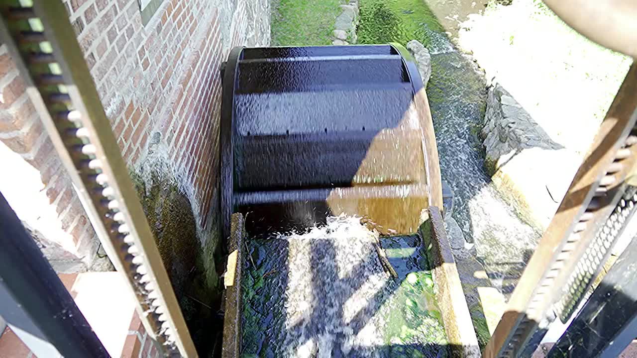 历史悠久的水磨的木磨轮在小溪的流水中转动视频素材