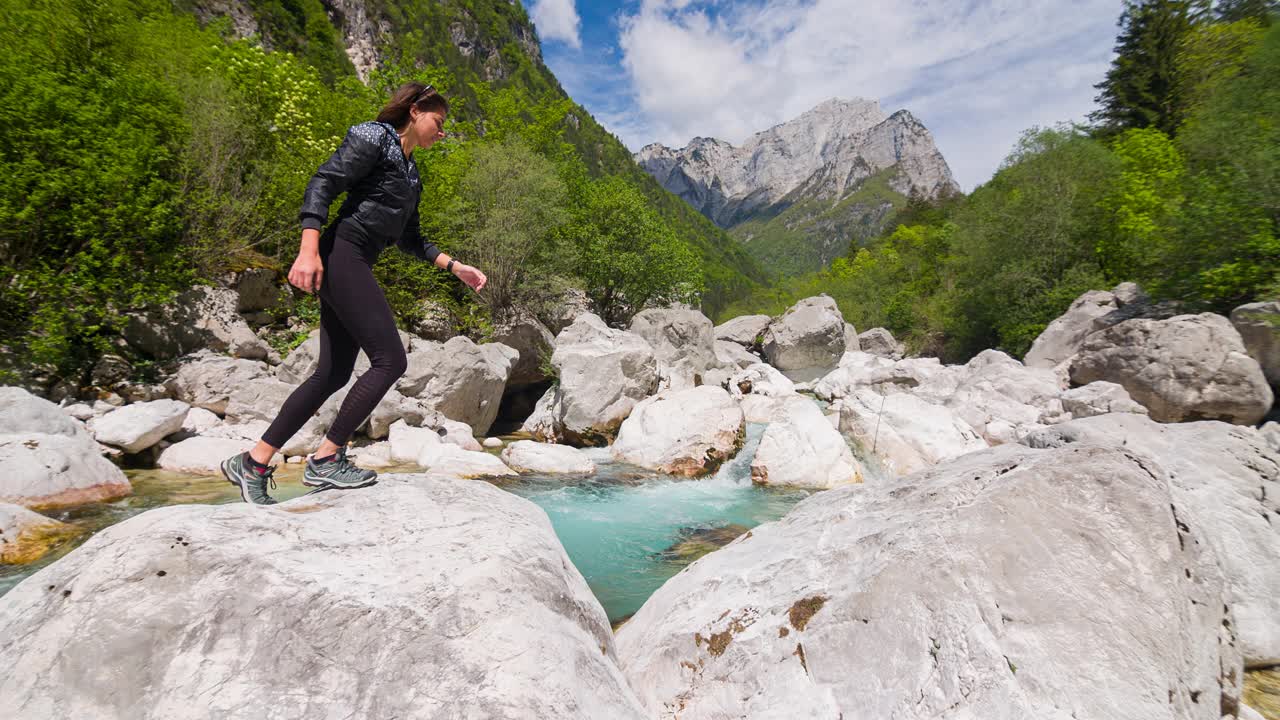 徒步旅行者跨越河流在山，跳过水溪视频素材