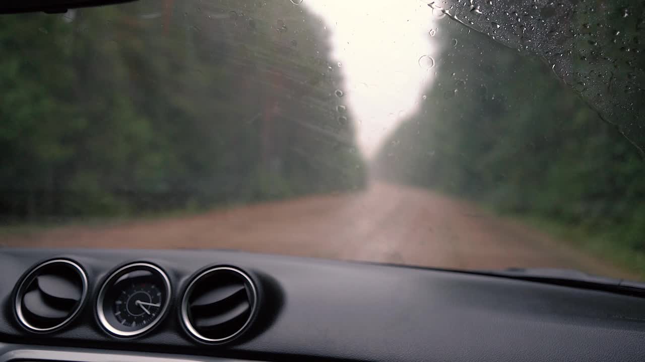 雨天在路上的汽车仪表盘和装有雨刷的前窗。视频素材