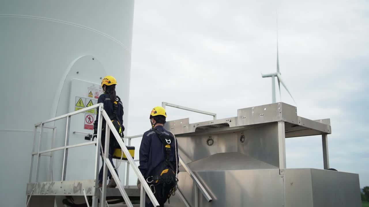 两名亚洲工程师统一检查工程师准备和进度检查风力涡轮机与安全在泰国风电场。视频素材