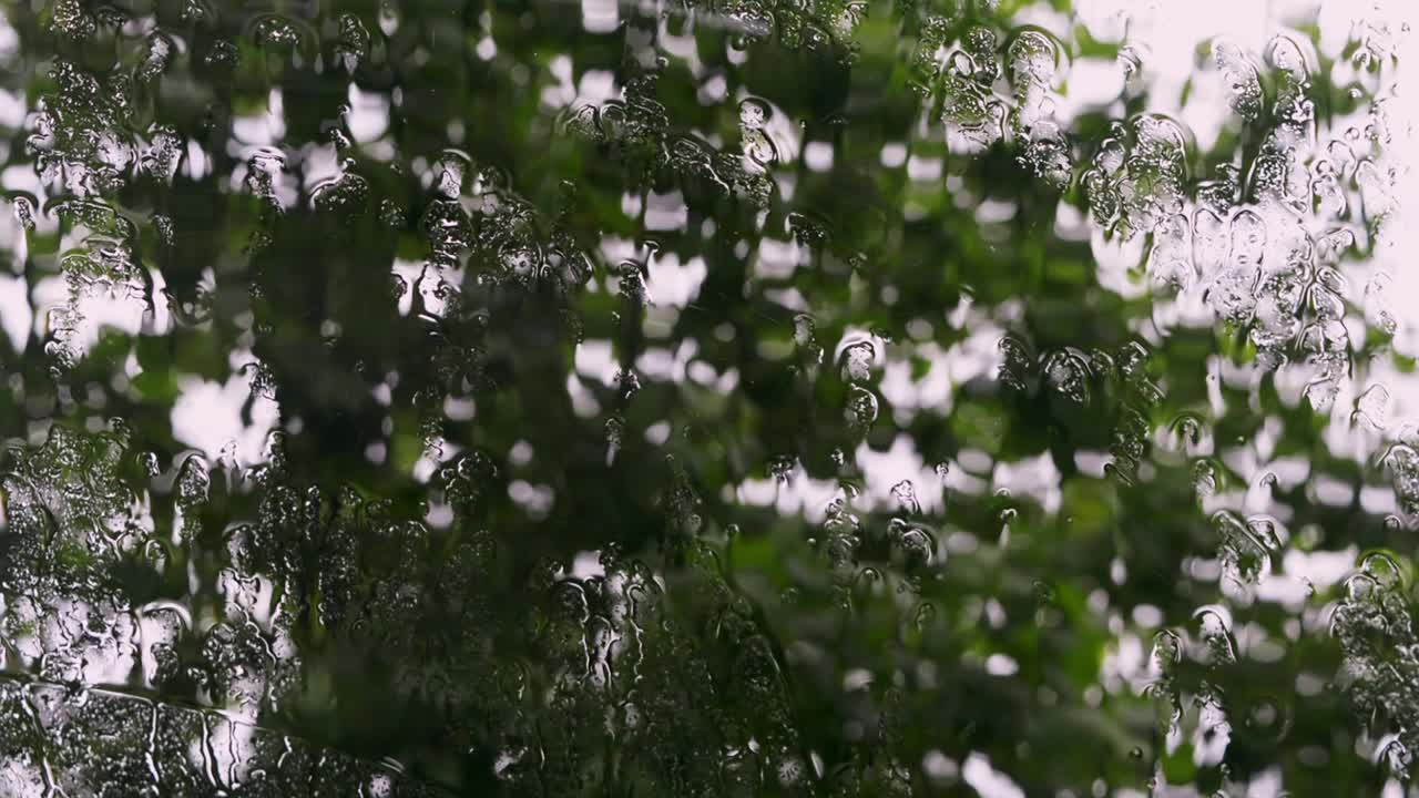 有雨滴的湿玻璃俯瞰着街道。视频下载