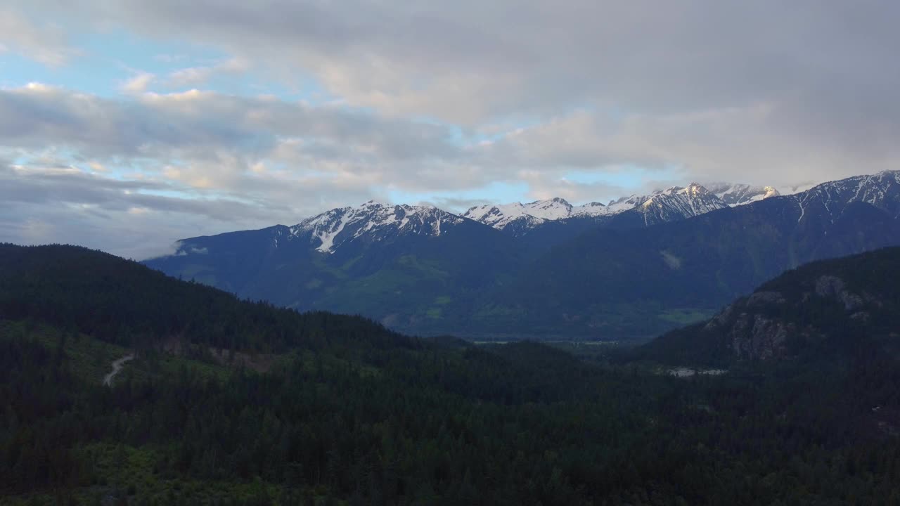 在加拿大的一个多云的日子，飞越绿色的山谷，飞向雪山视频素材