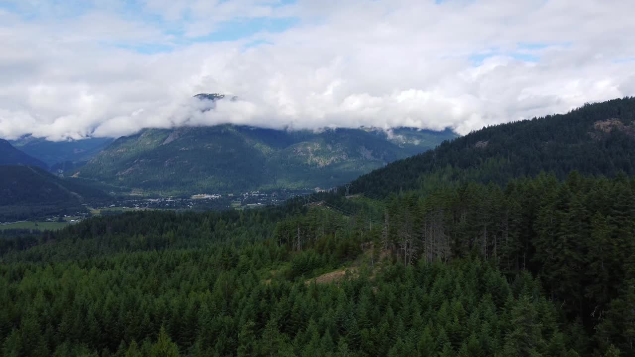 在一个阳光明媚的日子里，加拿大山谷在低云与绿色的森林小山视频素材