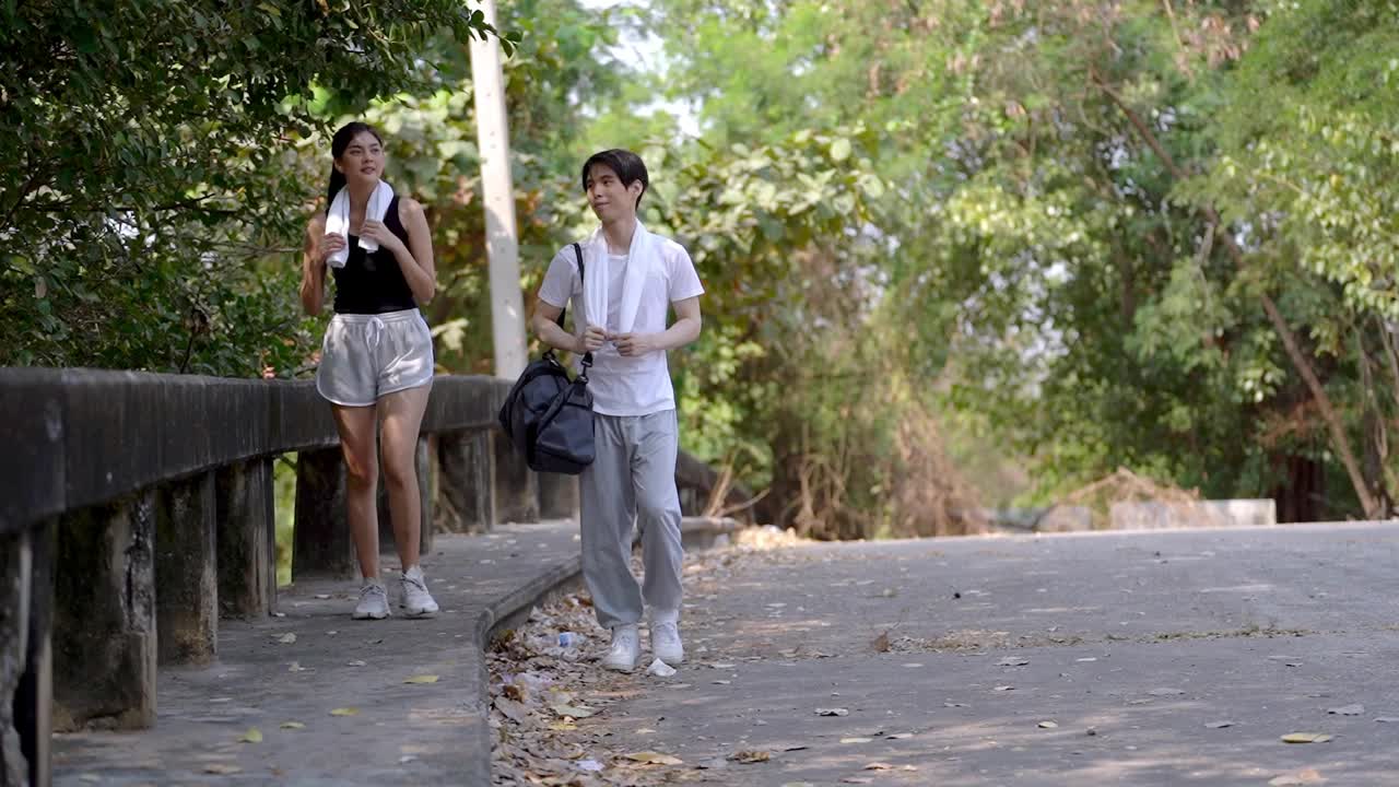 夏天，男女青年穿着运动服，在有自然和树木的户外空间跑步。人们步行和锻炼是为了健康的生活。视频素材