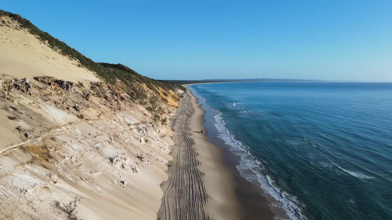 四轮驱动汽车沿着海浪旅行被壮观的侵蚀悬崖线旋转的彩色沙滩。视频素材