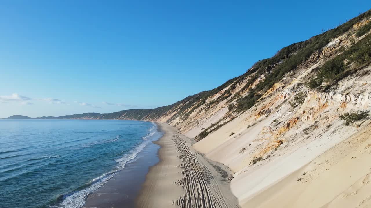 警车行驶在海浪和陡峭的沙崖之间，在废弃的海岸线海滩路上。视频素材