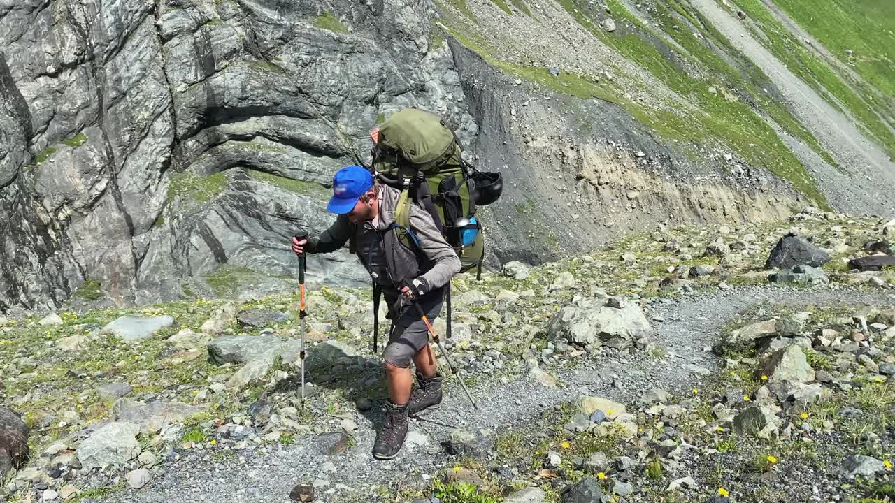 一个徒步旅行者背着一个大背包沿着山路走。从北部攀登卡兹别克视频素材