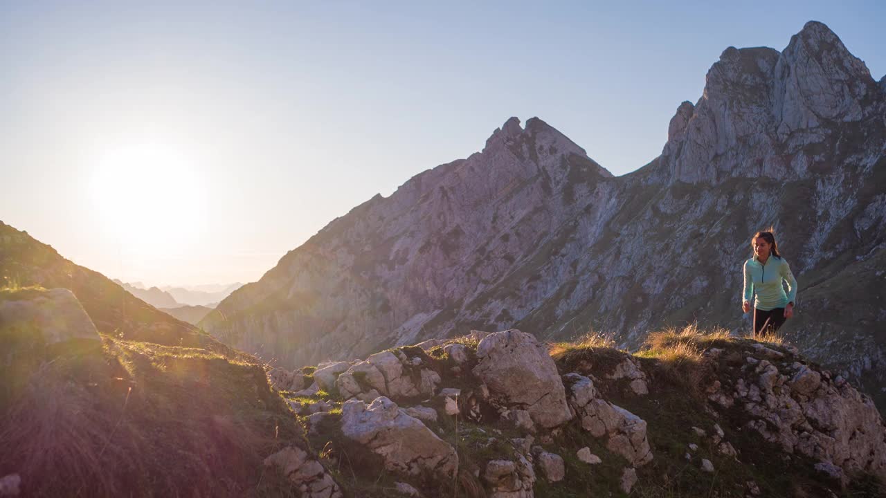 在高山地形中，沿着雄伟的石径和草坡向上奔跑视频素材