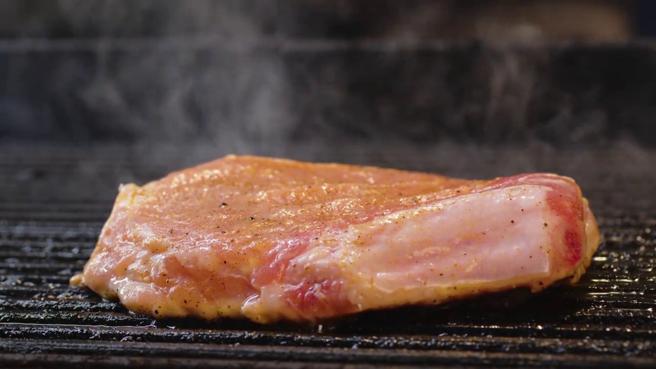 烤多汁的肉排与香料和香草在燃烧的木炭火在烧烤网格，火焰和烟雾。多汁牛排烧烤条纹准备野餐庆祝。烧烤架。视频素材