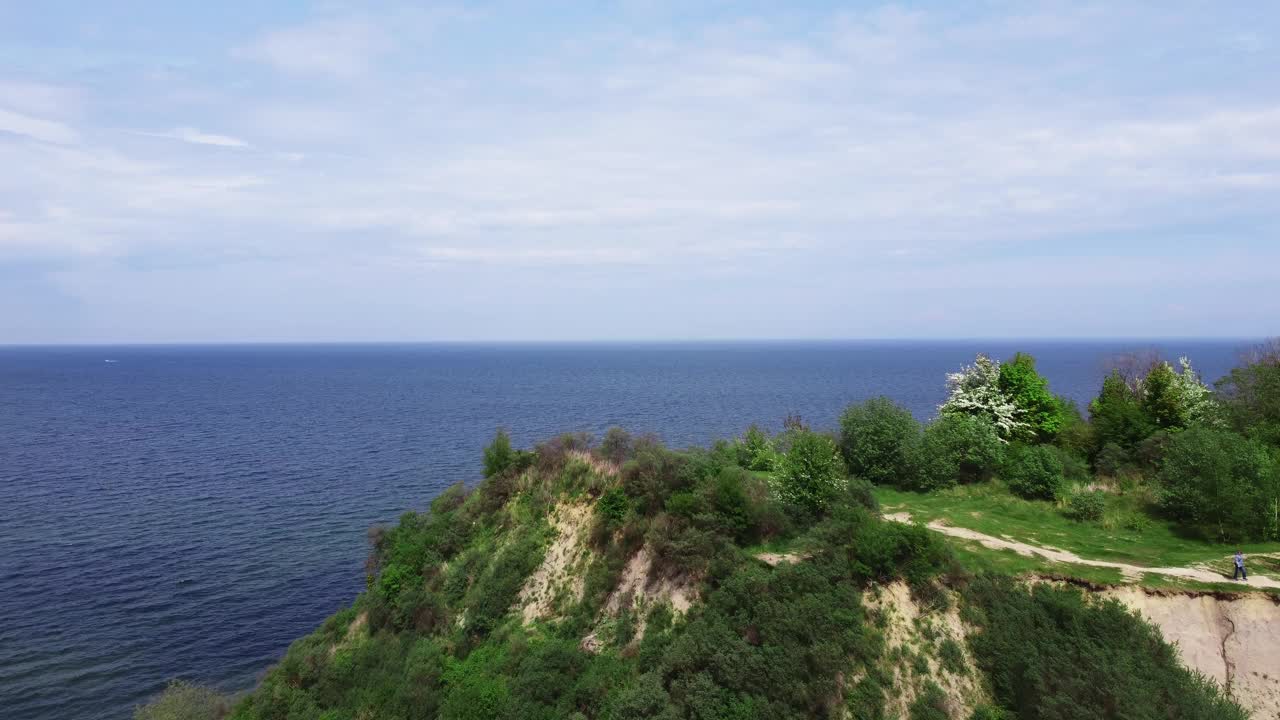 无人机从绿色的悬崖上拍摄的蓝色海洋在温暖的夏天的风景视频素材