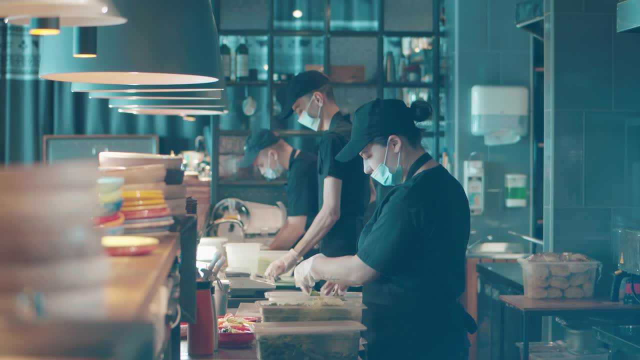 餐厅工作人员戴着口罩在开放式厨房做饭视频素材