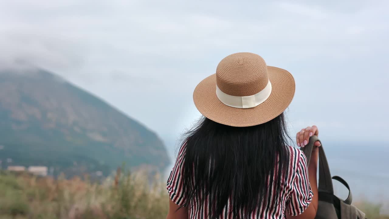 后视镜优雅女子旅行家背着背包走在山顶欣赏自然景观视频素材