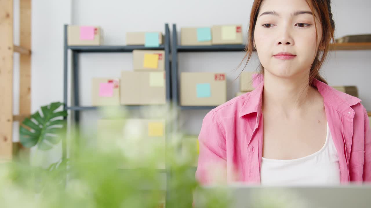 年轻的亚洲企业家女商人检查产品采购订单上的库存，并保存到电脑笔记本电脑工作在家里的办公室。视频素材