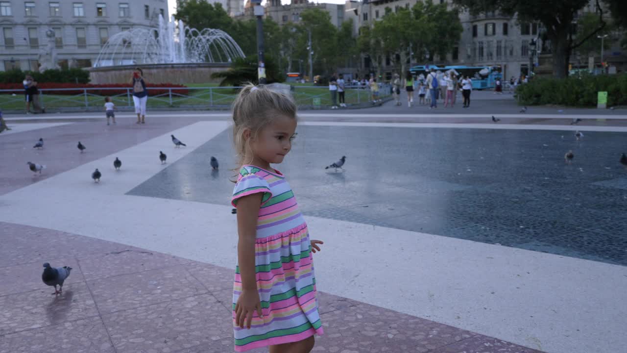 巴塞罗那的一个小女孩在Plaça Catalunya上追逐鸽子视频素材