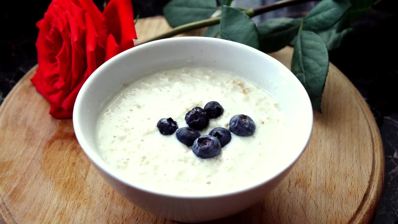 美味的成熟菠萝和蓝莓片落入一个白色的碗燕麦片。视频素材