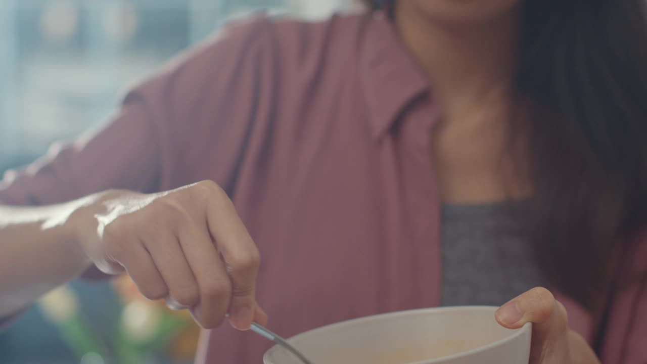 年轻的亚洲女厨师把鸡蛋搅拌到陶瓷碗里，在厨房桌子上的木板上用蔬菜做煎蛋卷。视频素材