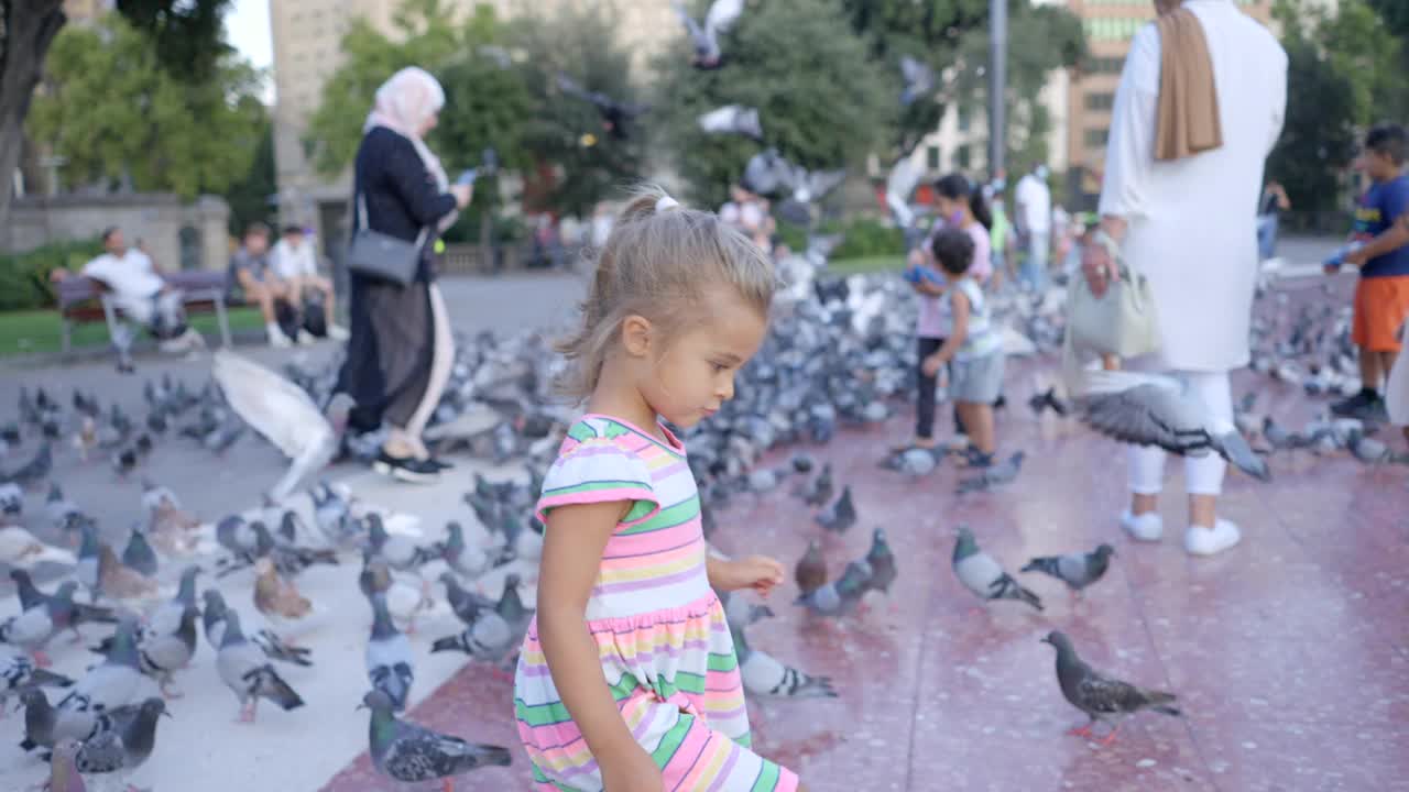 巴塞罗那的一个小女孩在Plaça Catalunya上追逐鸽子视频素材