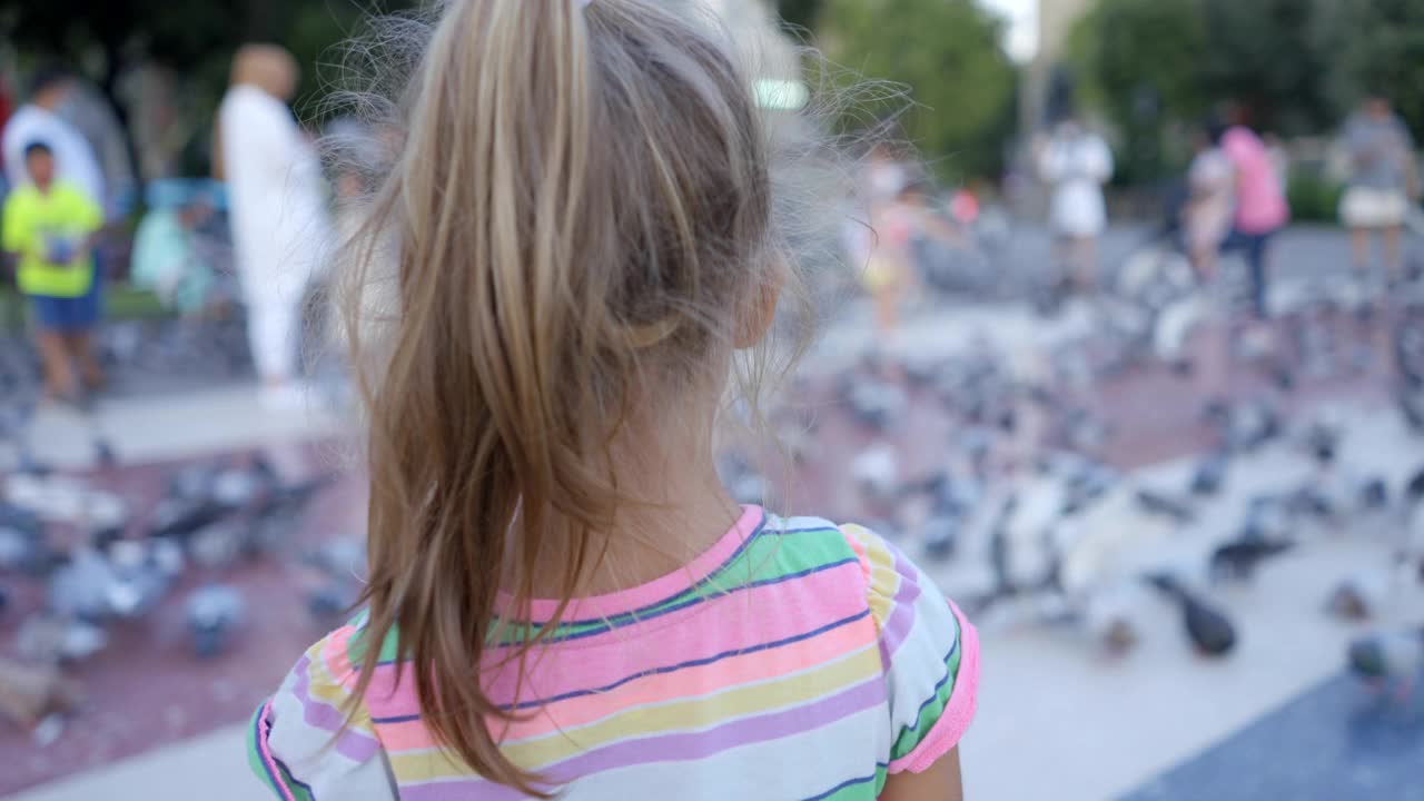 巴塞罗那的一个小女孩在Plaça Catalunya上追逐鸽子视频素材