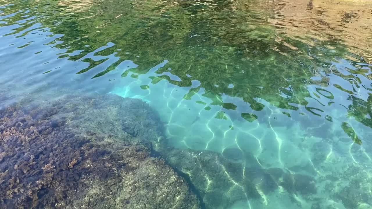 蓝绿色的海水泻湖的岩石地中海海岸。夏天美妙的海景。晶莹剔透、碧绿翠绿的海水背景。热带海浪。卵石滩。晶莹闪亮的水。视频素材