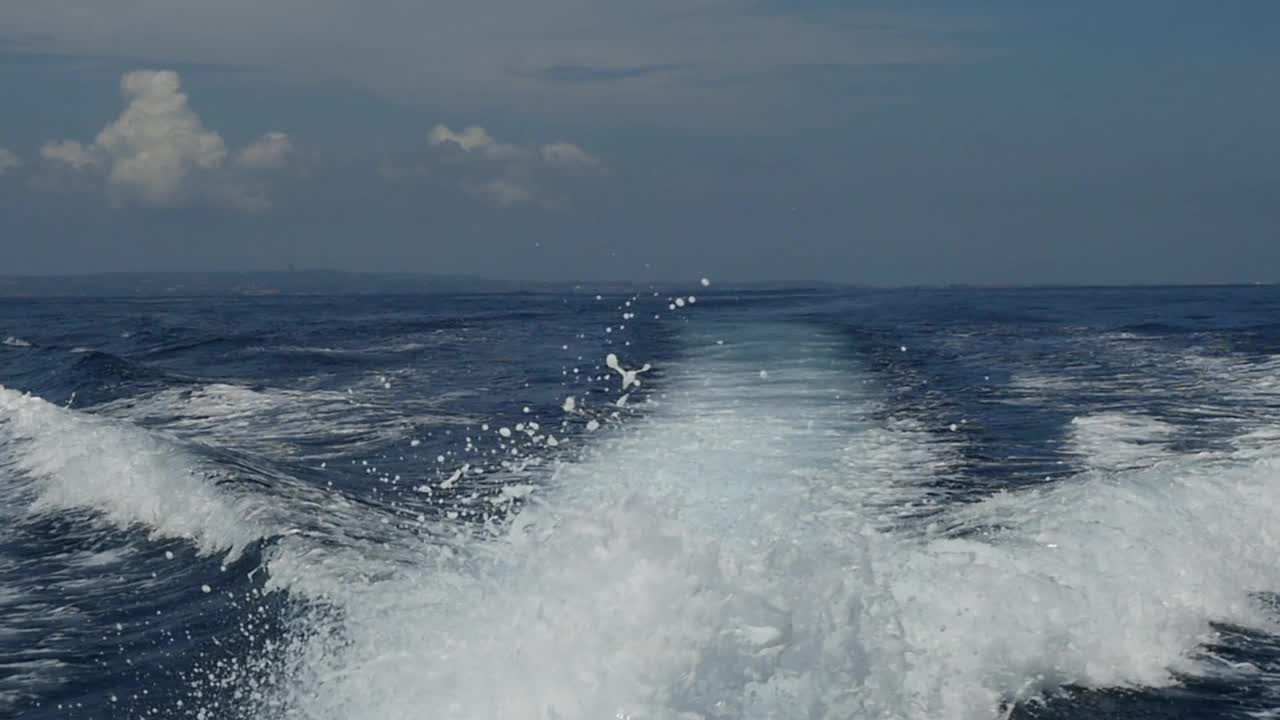 在印度尼西亚，一艘摩托艇发出的波浪以海洋地平线为背景。视频素材