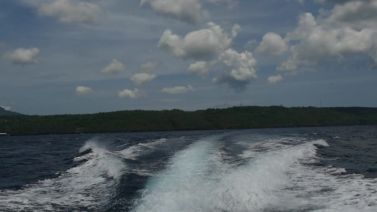 在印度尼西亚，一艘摩托艇发出的波浪以海洋地平线为背景。视频素材