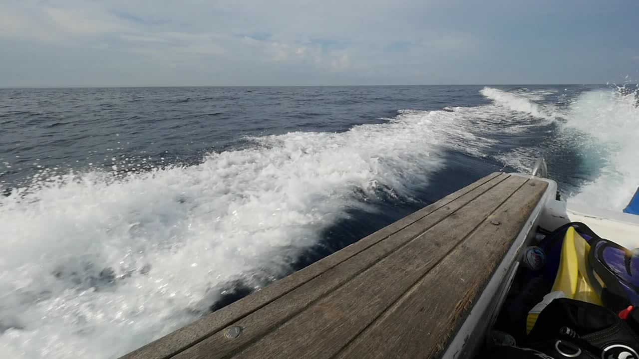 在印度尼西亚，一艘摩托艇发出的波浪以海洋地平线为背景。视频素材