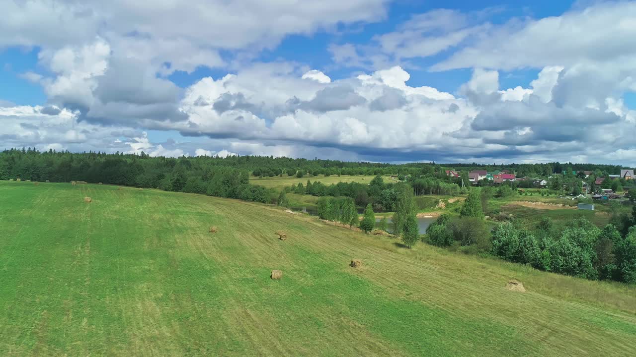 田园诗般的乡村。草地，干草田，村庄，大片白云。视频素材