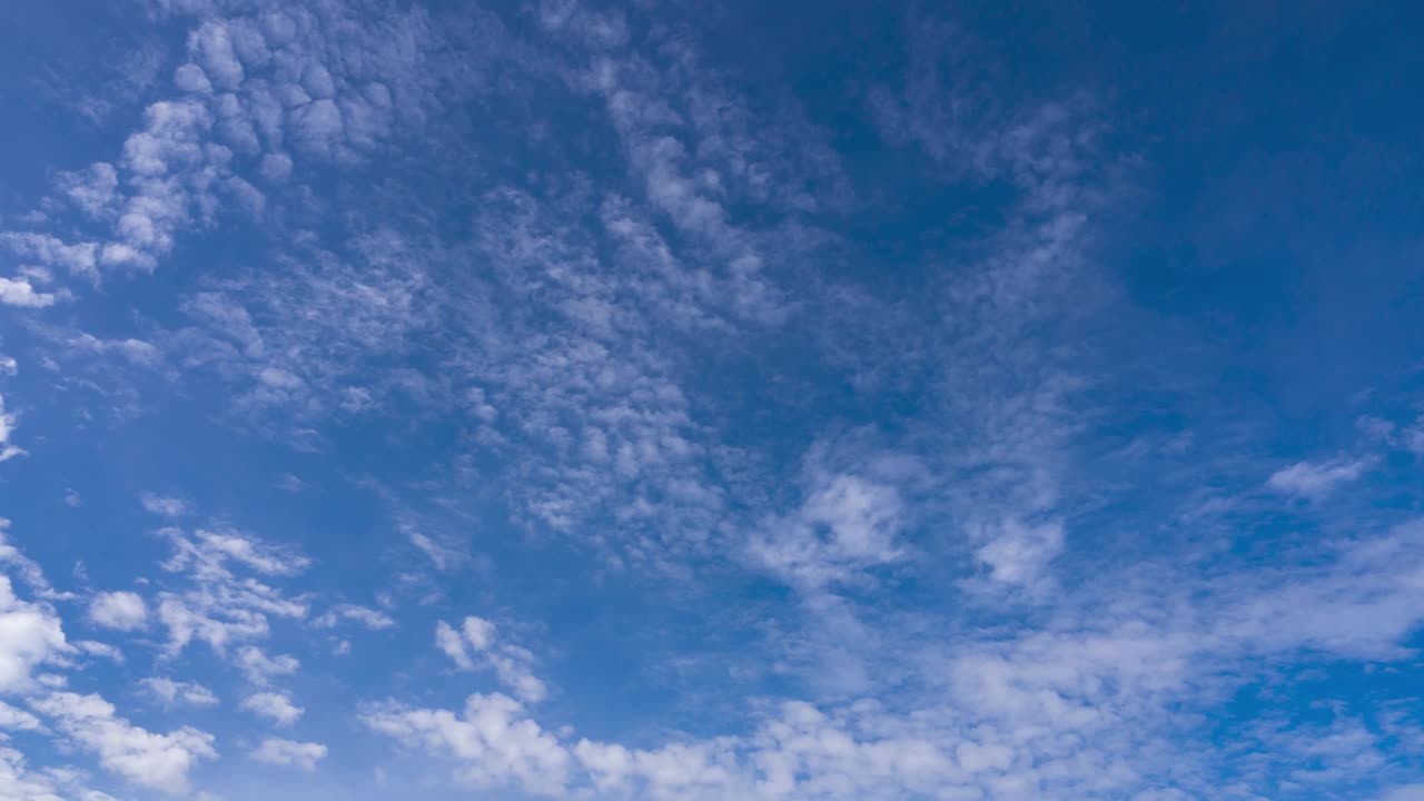 在夏日阳光明媚的日子里，云朵在晴朗的蓝天中移动。蓝蓝的天空飘着蓬松的白云，在春日晴空的广阔空间里遨游。视频素材