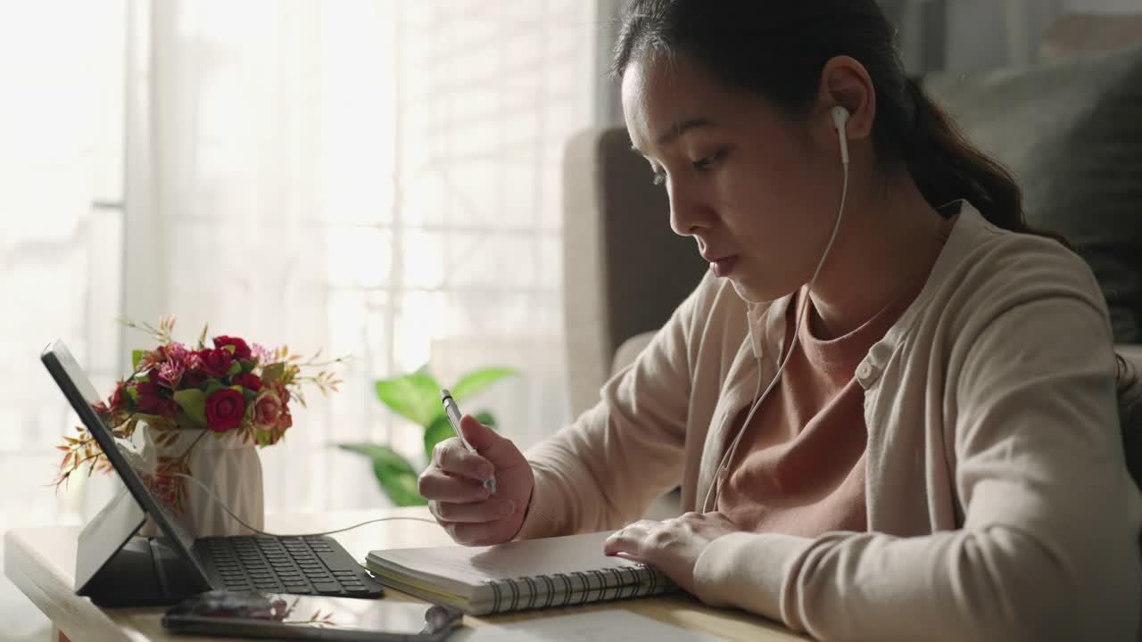 亚洲妇女戴着耳机和她的老师学习在笔记本电脑屏幕上在线家庭学校在线学习视频素材