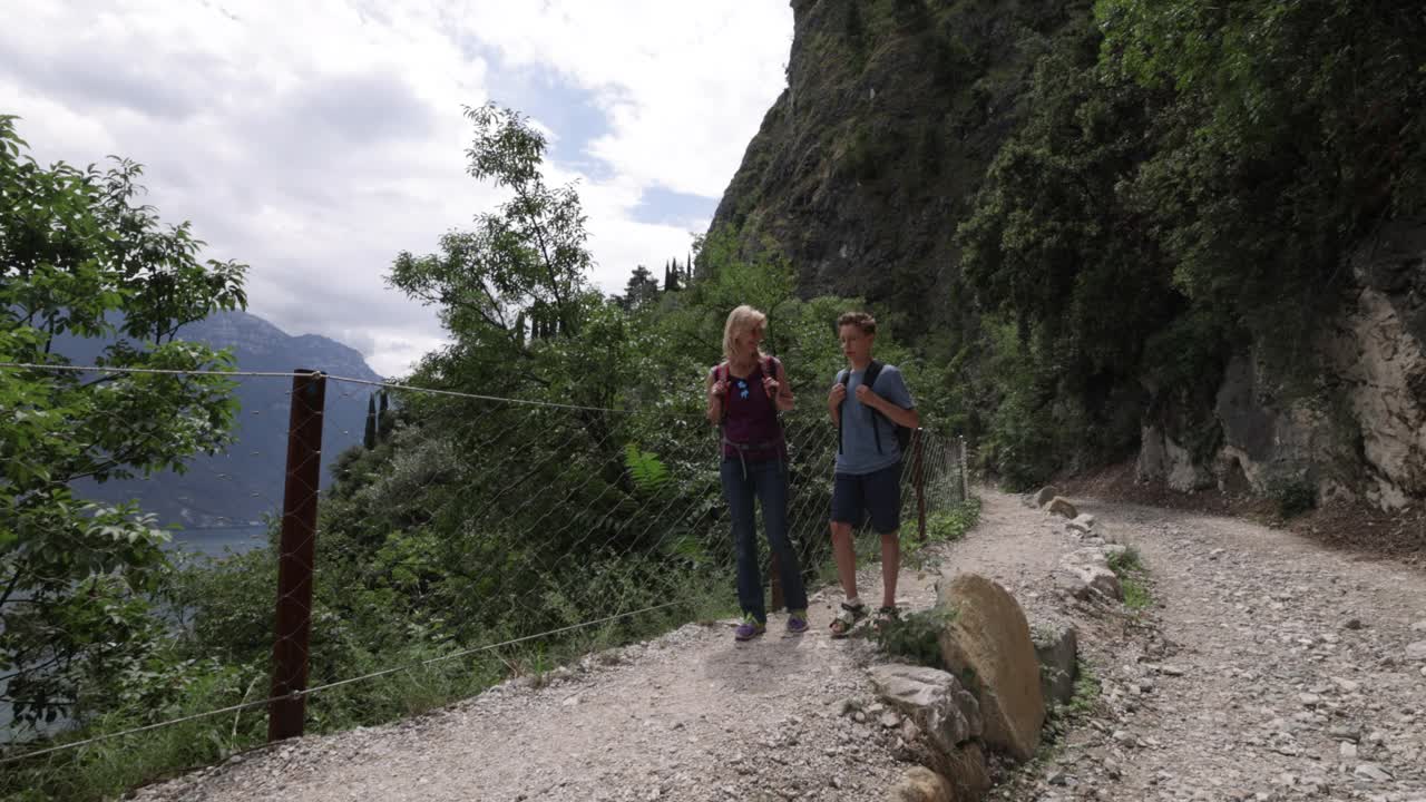 母亲和儿子在意大利加尔达湖旁的Ponale小径上徒步旅行视频素材