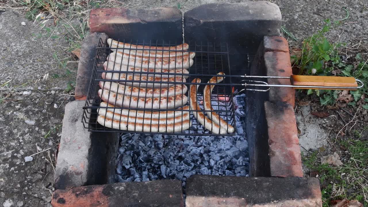 地面上有燃烧的煤炭和烤香肠的石制乡村炉子视频素材