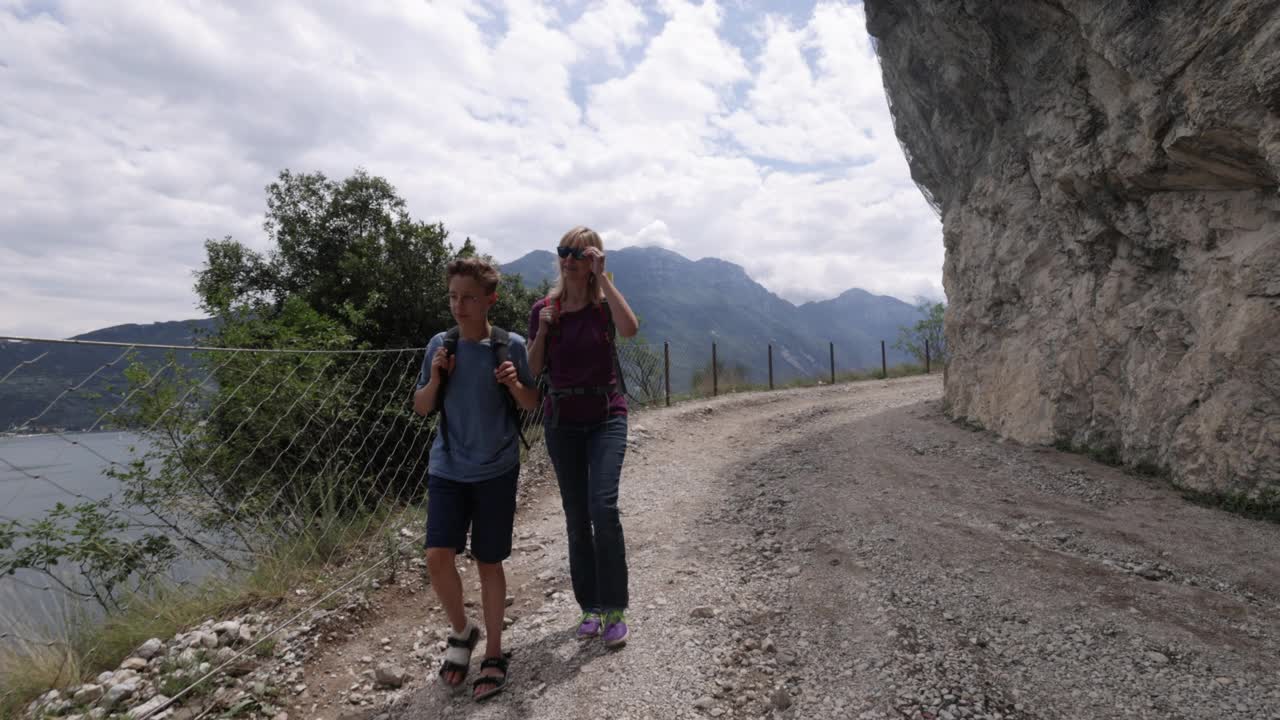 母亲和儿子在意大利加尔达湖旁的Ponale小径上徒步旅行视频素材