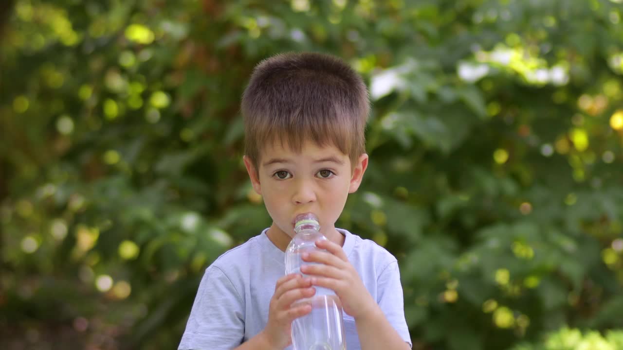 小男孩在户外喝塑料瓶里的水视频素材