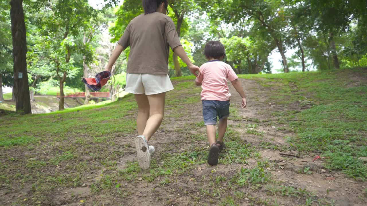 儿子和母亲一起在自然公园奔跑视频素材