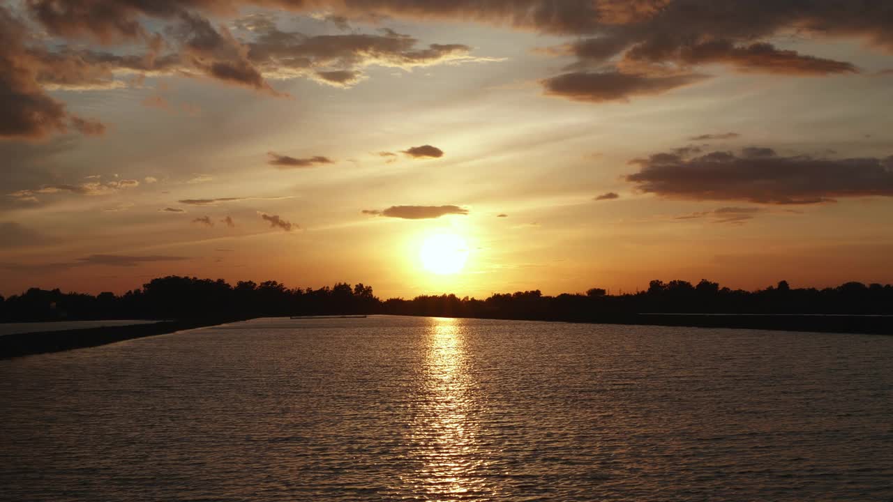 橘黄色的落日映照在湖面上，天空中的太阳倒映在水面上视频素材