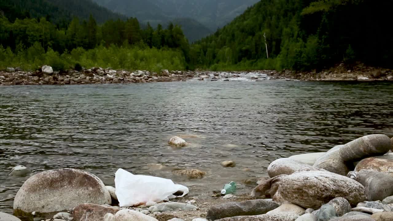 用塑料袋和瓶子污染森林中的河流。河中漂浮着垃圾。污染视频素材