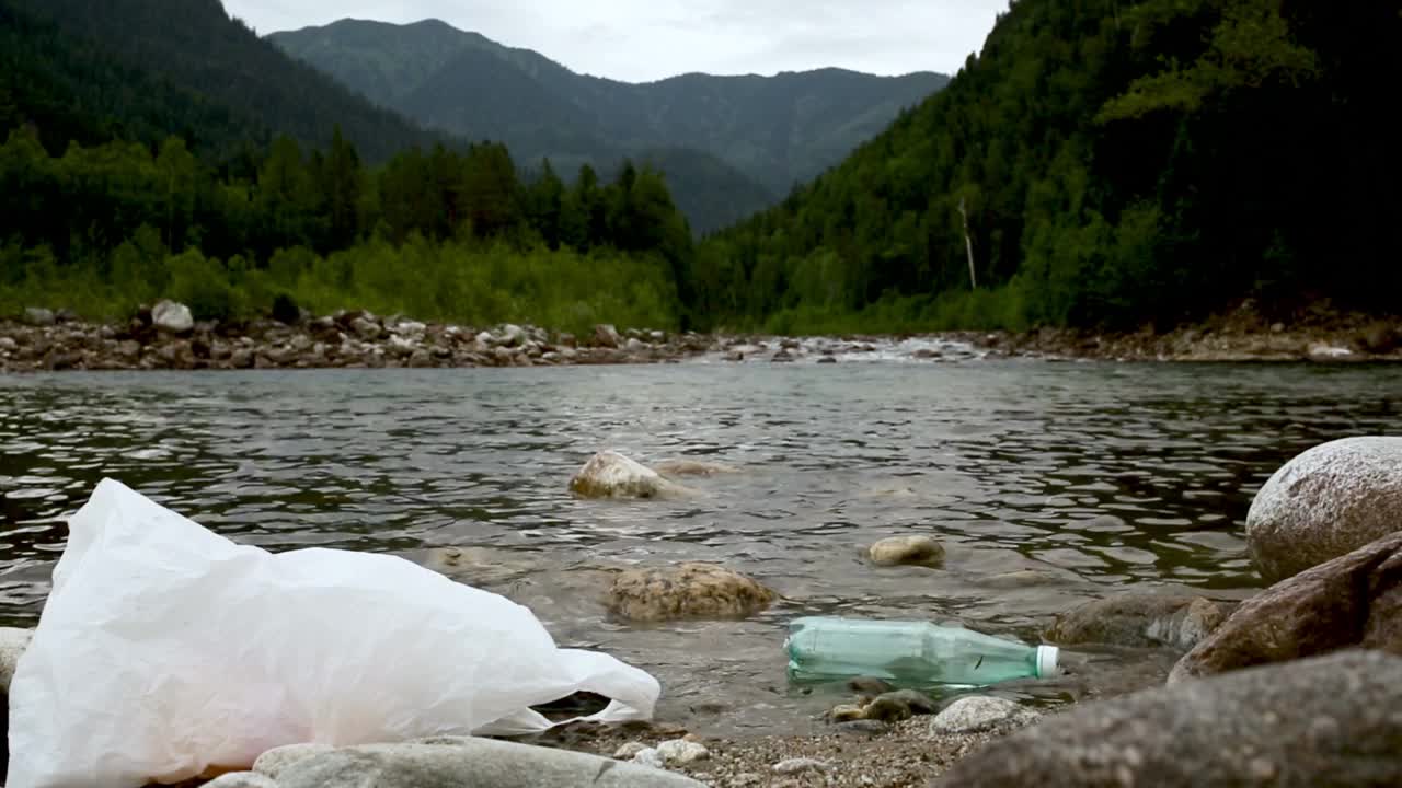 在森林里的河流里乱扔垃圾。我认为垃圾的瓶子和袋子污染生态视频素材