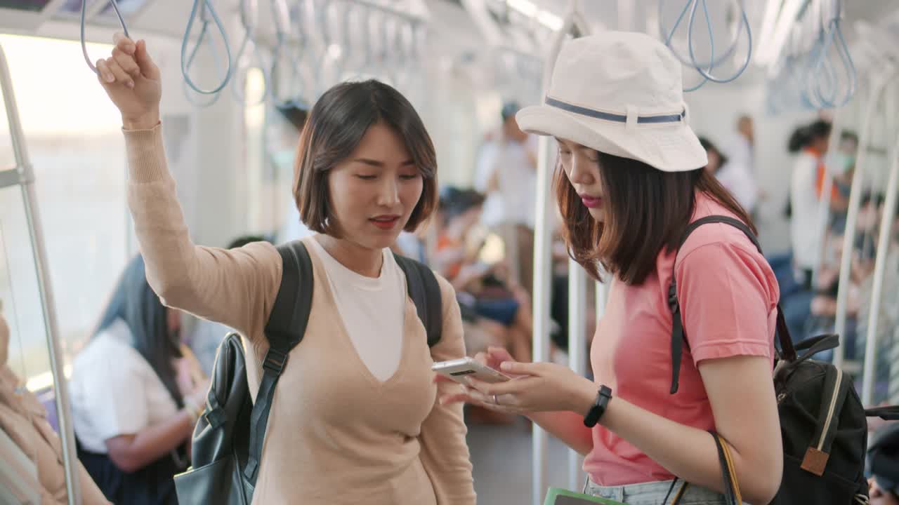 两个亚洲女人在火车上使用智能手机聊天，慢动作视频素材